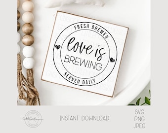 May include: A white wooden sign with black text that reads "Fresh Brewed Love is Brewing Served Daily" in a circle with two small hearts.