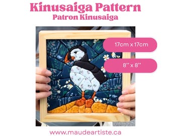 May include: A Kinusaiga pattern craft project featuring a puffin bird design in a light wood frame. The artwork measures 17cm x 17cm or 8 inches x 8 inches. The puffin is depicted with black, white, and orange fabric pieces against a dark floral background.