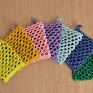 Peut inclure: Sept pochettes à savon en crochet dans un arc-en-ciel de couleurs, y compris le vert, le bleu, le violet, le rose, le jaune et l'orange. Les pochettes sont faites avec un motif de maille simple et ont une boucle pour accrocher.