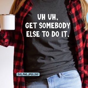 May include: A person wearing a black t-shirt with the text "UH UH, GET SOMEBODY ELSE TO DO IT." in white letters. The person is also wearing a red and black plaid shirt and blue jeans.