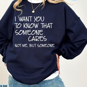 May include: A navy blue sweatshirt with the text "I want you to know that someone cares, not me, but someone" printed in white.