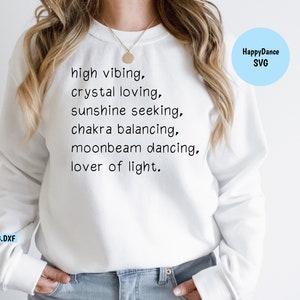 May include: White sweatshirt with the text "high vibing, crystal loving, sunshine seeking, chakra balancing, moonbeam dancing, lover of light." The text is in black and centered on the sweatshirt.