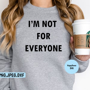 May include: A gray sweatshirt with the text "I'M NOT FOR EVERYONE" printed on the front. The sweatshirt is being worn by a person holding a coffee cup.