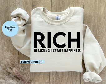 May include: A beige sweatshirt with the text "RICH" in large black letters and the text "REALIZING I CREATE HAPPINESS" in smaller black letters below.