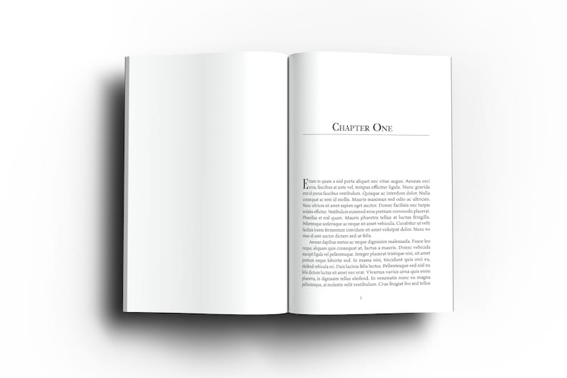 May include: An open book with white pages, displaying the text "CHAPTER ONE" at the top of the right page. The text is in a serif font. The left page is blank. The book is on a white surface.