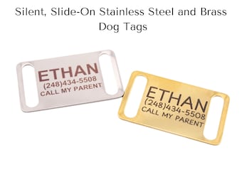 Puede incluir: Dos placas de identificación rectangulares para perros, una plateada y otra dorada, con extremos redondeados y ranuras para sujetar. La placa plateada tiene el nombre "ETHAN" y un número de teléfono. La placa dorada tiene la misma información.