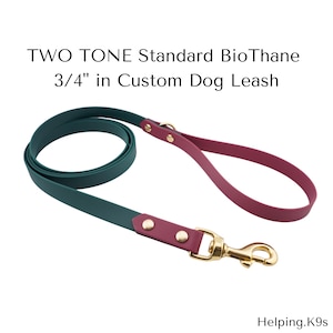 Könnte beinhalten: Zweifarbige Hundeleine in Grün und Burgunderrot. Die Leine ist etwa 1,9 cm breit und hat goldfarbene Beschläge. Der Text "TWO TONE Standard BioThane 3/4" in Custom Dog Leash" ist sichtbar.