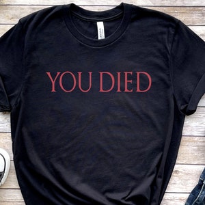 May include: Black t-shirt with the text "YOU DIED" in red lettering.