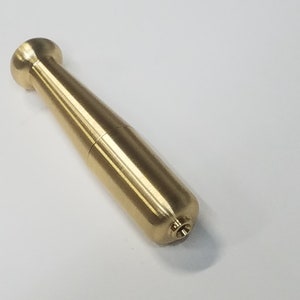 May include: A gold-colored metal object shaped like a small, rounded baseball bat.