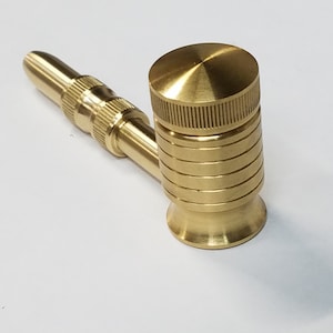 May include: A gold metal pipe with a round bowl and a long, straight stem. The bowl has a textured design and the stem has a smooth finish.