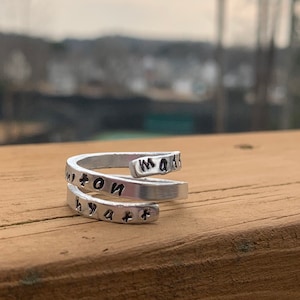 May include: A silver ring with the words "Madison" and "Wyatt" engraved on it.