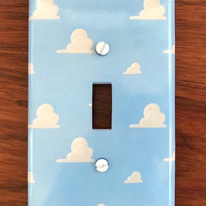 May include: A light blue light switch cover with a white cloud pattern. The cover has two white screws.