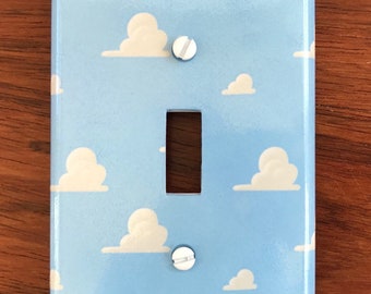 May include: A light blue light switch cover with a white cloud pattern. The cover has two white screws.