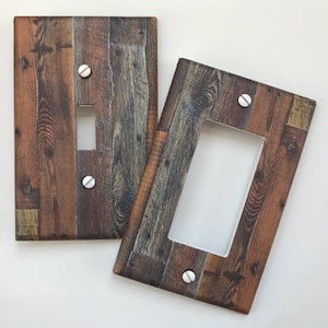 May include: Two decorative light switch covers with a wood grain pattern. One cover has a single switch opening, and the other has a larger rectangular opening. Both are secured with silver screws, and the wood grain features shades of brown, gray, and orange.