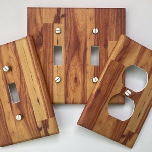 May include: Four wood-grain patterned wall plates for light switches and outlets. Two single-switch plates, one double-switch plate, and one double-outlet plate.