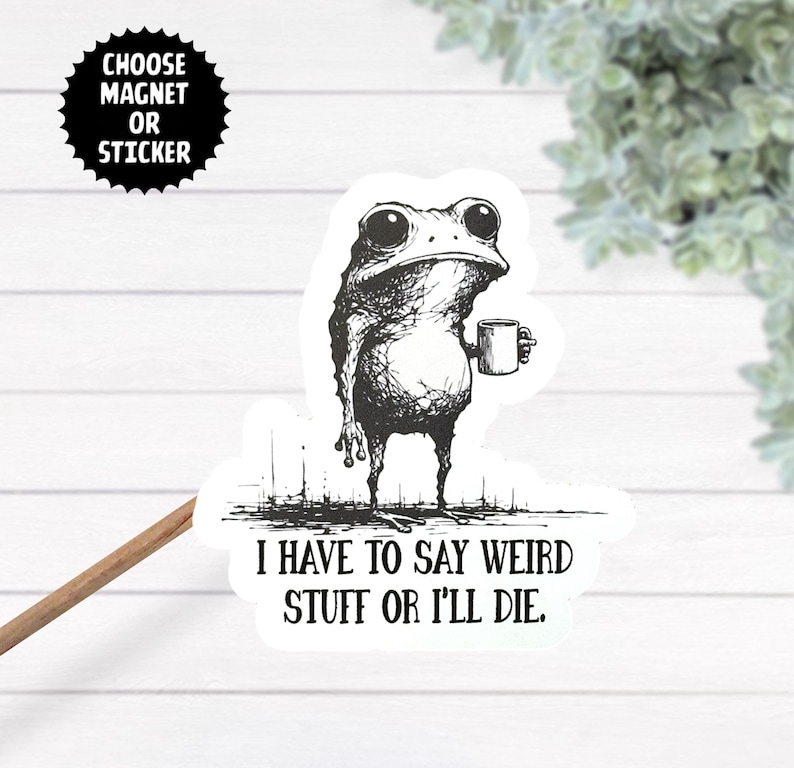 May include: Black and white sticker or magnet featuring a quirky frog holding a mug. The frog has large eyes and a slightly grumpy expression. Text reads "I HAVE TO SAY WEIRD STUFF OR I'LL DIE." A circular black graphic says "CHOOSE MAGNET OR STICKER."