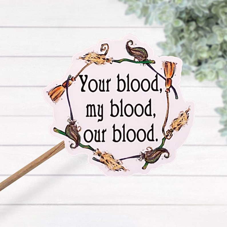 May include: A pink circle sticker with a wreath of broomsticks and the text "Your blood, my blood, our blood."