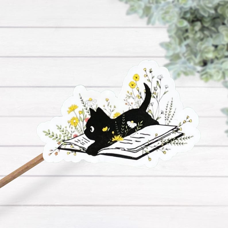 May include: A black cat silhouette reading a book surrounded by yellow, white, and pink flowers.