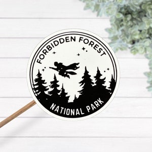 May include: Black and white sticker with a circular design. The sticker features a silhouette of a person flying on a broomstick in front of a forest. The text "Forbidden Forest National Park" is written around the edge of the sticker.
