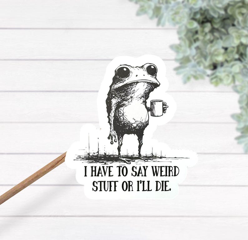 May include: A black and white sticker featuring a quirky frog holding a mug. The frog has large eyes and a slightly grumpy expression. The sticker includes the text: "I HAVE TO SAY WEIRD STUFF OR I'LL DIE."