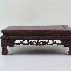 May include: A dark brown wooden table with a carved design on the bottom shelf. The table has four legs and a rectangular top.