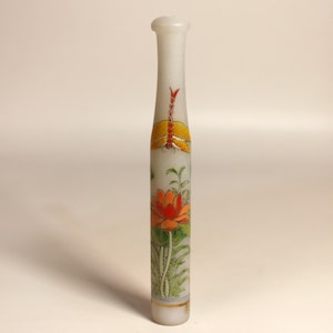 May include: A tall, white, cylindrical decorative object with a rounded top. It features a painted design of a dragonfly and a lotus flower in orange, yellow, and green. The base has a gold band.