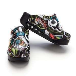 May include: A pair of black clogs with a colorful, graphic print featuring medical symbols and designs. The clogs have a thick, black sole with a slight lift.