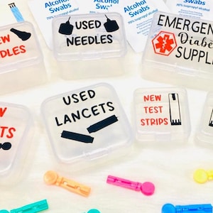 May include: Six clear plastic containers with red and black labels for storing diabetic supplies. The containers are labeled "New Needles", "Used Needles", "New Lancets", "Used Lancets", "New Test Strips", and "Used Test Strips". There is also a larger container labeled "Emergency Diabetic Supplies" with a red star of life symbol.