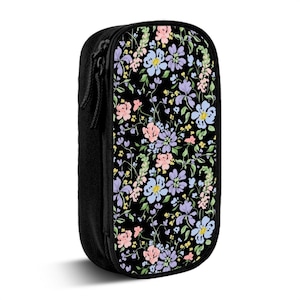May include: Black pencil case with a floral pattern. The case features a black zipper and a colorful floral design with pink, blue, and purple flowers on a black background. The case is rectangular and upright.