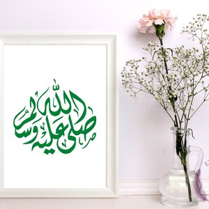 Puede incluir: Una impresión enmarcada en blanco con un diseño de caligrafía árabe verde. El diseño dice "Allah" y "Muhammad" en árabe.