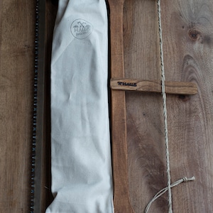 May include: A wooden saw with a canvas sheath. The saw is made of wood and has a metal blade. The sheath is made of canvas and has a leather strap. The saw is labeled "X HALLS" and the sheath is labeled "HALLS DÜSCHEREI".