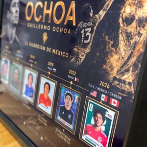 May include: A framed commemorative poster featuring Guillermo Ochoa, with gold text reading OCHOA, 5 MUNDIALES - UNA LEYENDA, and EL GUARDI&Aacute;N DE M&Eacute;XICO. It displays a goalkeeper silhouette, the FIFA World Cup trophy, and a timeline of player cards from 2006 to 2026.