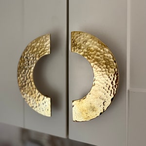 Puede incluir: Dos tiradores de armario de medio círculo martillados en oro.