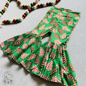 Può includere: Pantaloni a zampa d'elefante verdi con un motivo a bastoncino di zucchero bianco e rosso. I pantaloni hanno un motivo a biscotto di pan di zenzero marrone.