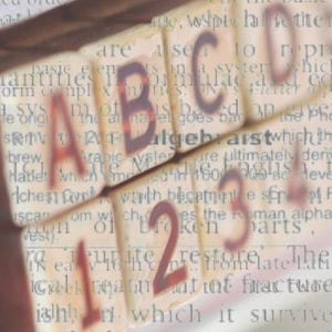 Peut inclure: Gros plan sur des blocs d'alphabet &eacute;pellant "ABC" et des blocs de nombres &eacute;pellant "123". Les blocs sont en bois et ont un aspect vintage. Les blocs sont pos&eacute;s sur une page de texte sur l'histoire de l'alphabet.