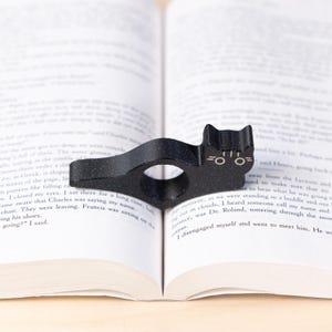Black tabby cat thumb book page holder with bookmark, ergonomic and playful design, perfect gift for book lovers, adds charm to reading, ideal for birthdays, anniversaries, or as a stocking stuffer, a practical and adorable reading companion