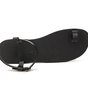 May include: Black leather thong sandals with a buckle closure and a palm tree logo on the sole.