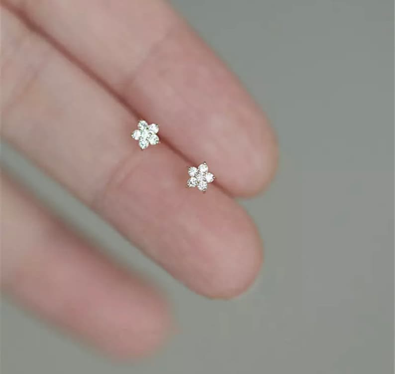 May include: A pair of small, delicate flower-shaped earrings with clear cubic zirconia stones.