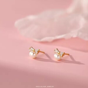 May include: A pair of gold-tone earrings with a pearl and a small bow-shaped crystal design.  925 Silver Jewelry.