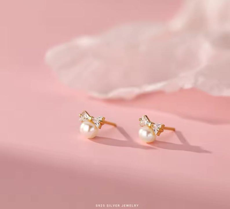 May include: A pair of gold-tone earrings with a pearl and a small bow-shaped crystal design.  925 Silver Jewelry.