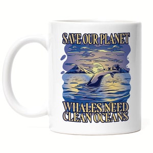Op de afbeelding: Witte keramische mok met een walvis die uit het water springt, tegen een achtergrond van een zonsondergang. De mok heeft de tekst "SAVE OUR PLANET" en "WHALES NEED CLEAN OCEANS" in blauw en geel. De mok heeft een wit handvat.