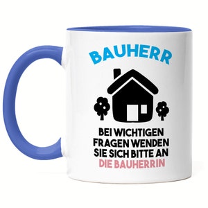 Könnte beinhalten: Weiße Keramiktasse mit blauem Rand und Henkel. Die Tasse hat eine schwarz-weiße Illustration eines Hauses mit zwei Bäumen und dem Text "Bauherr Bei wichtigen Fragen wenden Sie sich bitte an die Bauherrin".