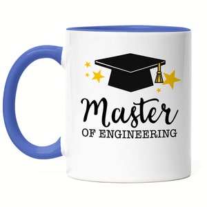 Könnte beinhalten: Weiße Keramik-Kaffeetasse mit blauem Rand und Henkel. Die Tasse zeigt eine schwarze Abschluss-Kappe mit goldener Quaste und den Text "Master of Engineering" in Schwarz.