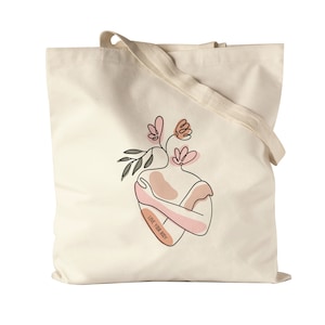 Peut inclure: Un sac fourre-tout beige avec un motif floral et le texte "LOVE YOUR BODY" imprimé dessus.