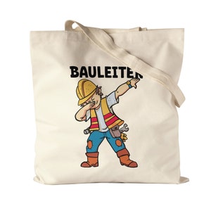 Può includere: Una borsa tote in tela bianca con testo nero che dice "BAULEITER" e un'illustrazione di un cartone animato di un operaio edile che fa il ballo "dab". L'operaio indossa un casco giallo, un giubbotto di sicurezza, jeans blu e stivali marroni.