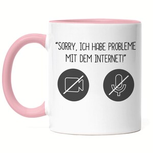 Könnte beinhalten: Weiße Keramiktasse mit rosafarbenem Rand und Henkel. Die Tasse hat eine schwarz-weiße Grafik einer durchgestrichenen Videokamera und eines Mikrofons mit dem Text "SORRY, ICH HABE PROBLEME MIT DEM INTERNET!"