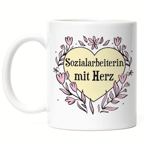 Könnte beinhalten: Weiße Keramiktasse mit einem pinkfarbenen und gelben Herzdesign. Das Herz enthält den Text "Sozialarbeiterin mit Herz".