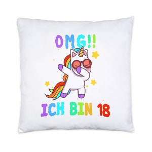Peut inclure: Un oreiller blanc avec un dessin animé coloré d'une licorne portant des lunettes de soleil et faisant le dab. Le texte "OMG!! ICH BIN 18" est imprimé sous la licorne.