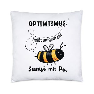 Può includere: Un cuscino bianco con un'ape di cartone animato nera e gialla e il testo "Optimismus heisst umgedreht Sumsi mit Po."