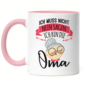 Può includere: Tazza in ceramica bianca con manico e interno rosa. La tazza presenta un'illustrazione a cartoni animati di una nonna con occhiali e chignon, e il testo tedesco "Ich bin die Oma" (Io sono la nonna).